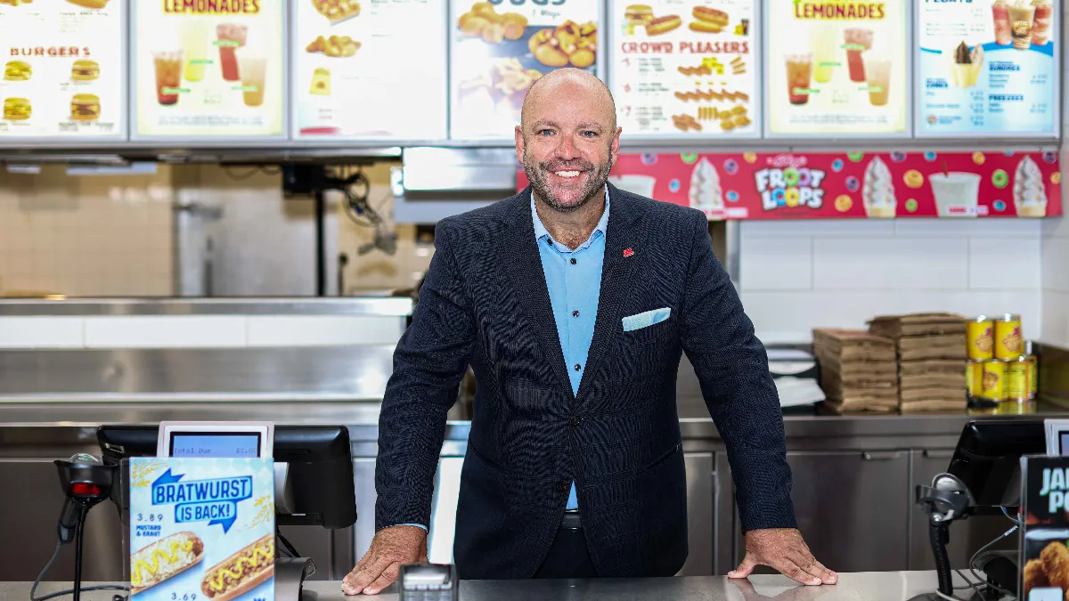 An image of a man standing in front of a menu.