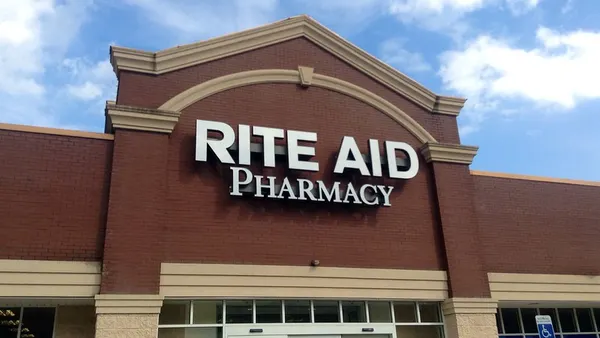 A pharmacy storefront against a bright blue sky with puffy white clouds.
