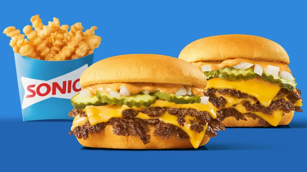 A photo of crinkle fries in a box that says Sonic and two burgers next to each other in front of a blue backdrop.