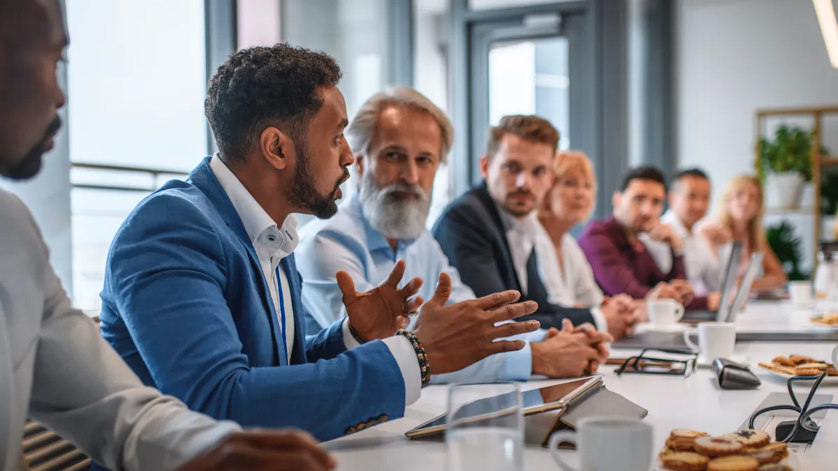 Determined businessman expressing opinions to junior and senior colleagues on management team in conference room