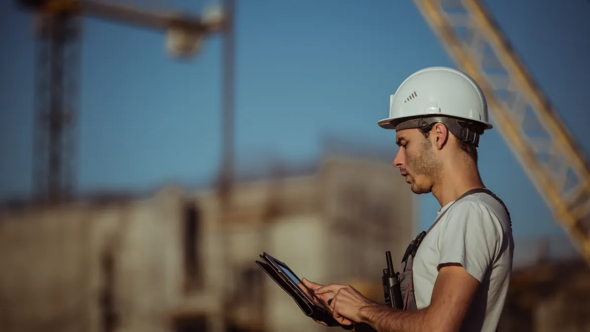 A construction worker holding tablet and working outside