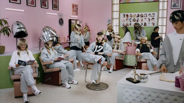 A group of people in grey sweatpants and hoodies pose inside a hair salon.