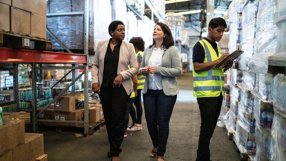 Co-workers talk while walking in a warehouse