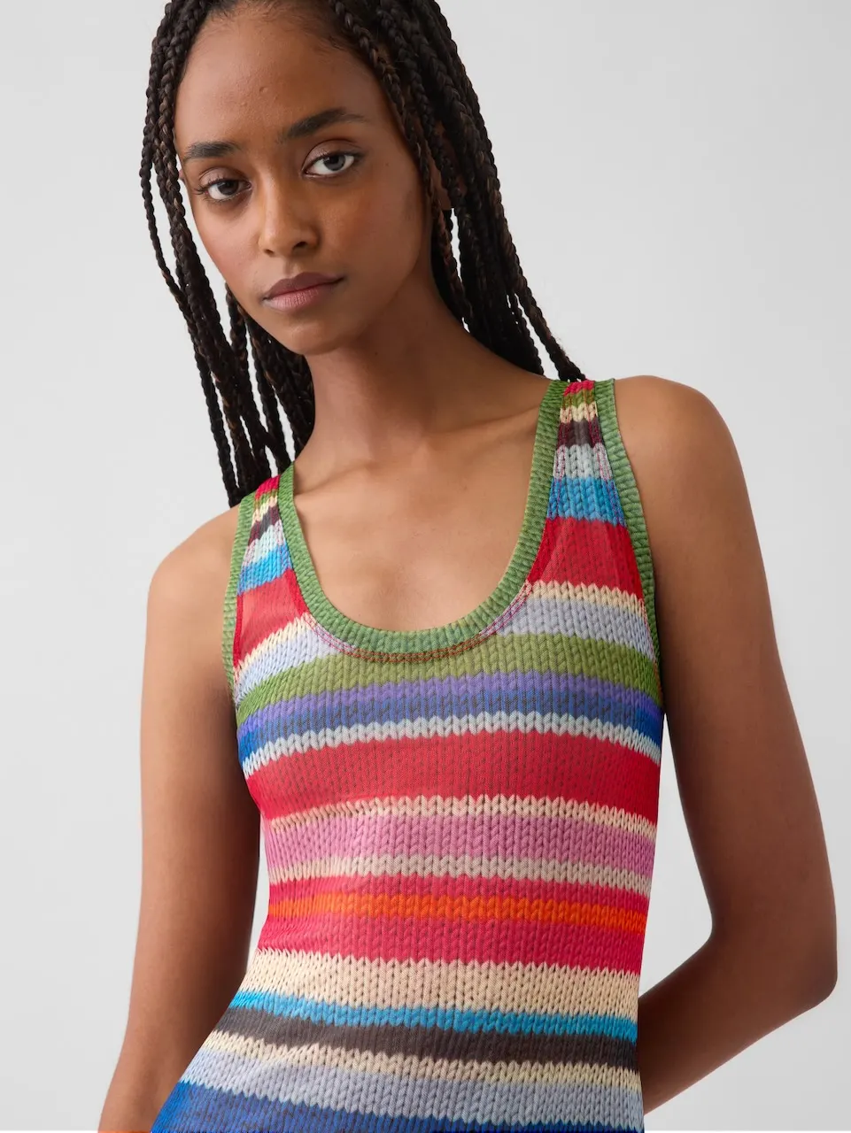 A person with long hair wearing a striped tank top.