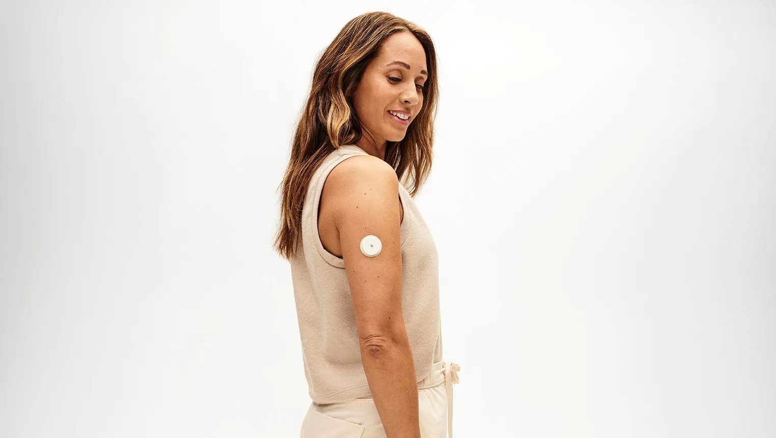 A person stands with a white, circular device attached to their upper arm.