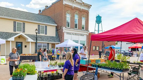 Farmers market with red tents in front of a brick building