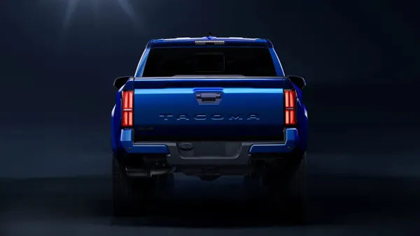 The tailgate and rear lights on a blue 2024 Toyota Tacoma TRD Sport pickup viewed from behind.