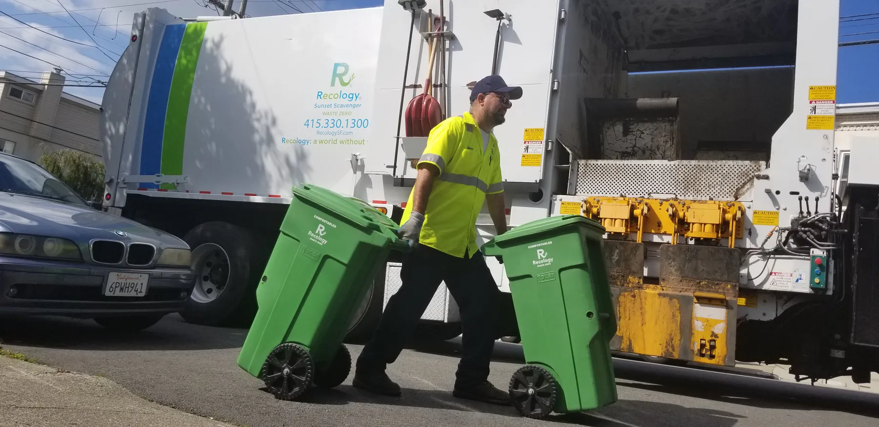 A Recology employee collects green curbside compostable material bins.