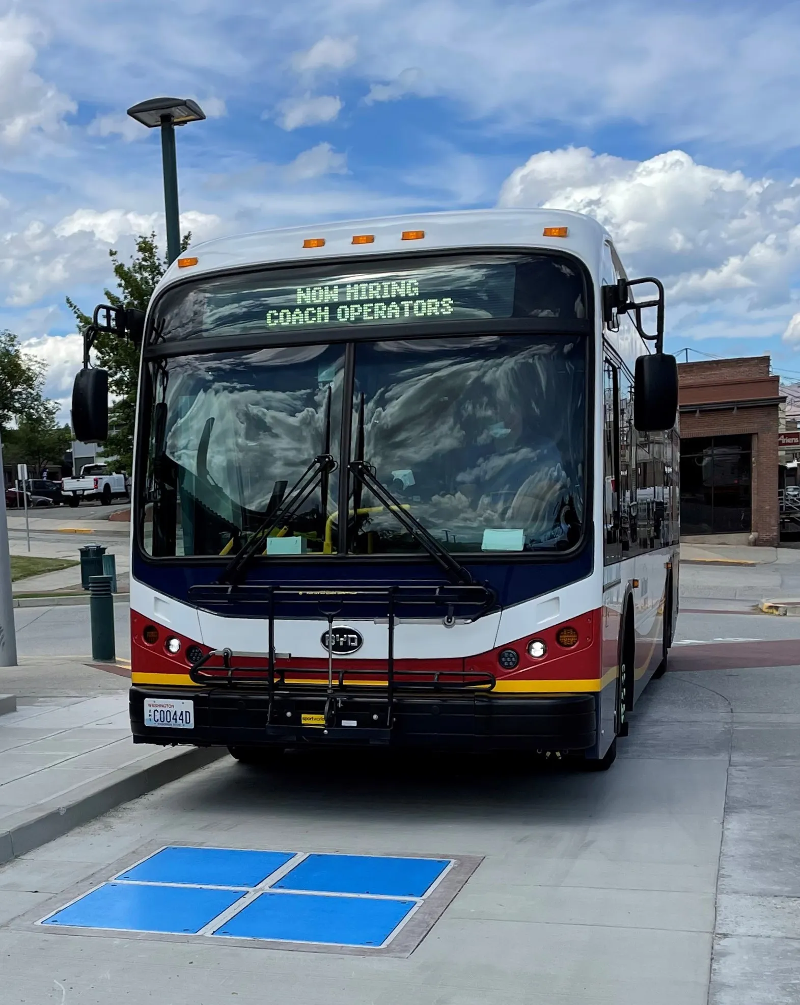 A bus approaches wireless charging pad embedded in the roadway.