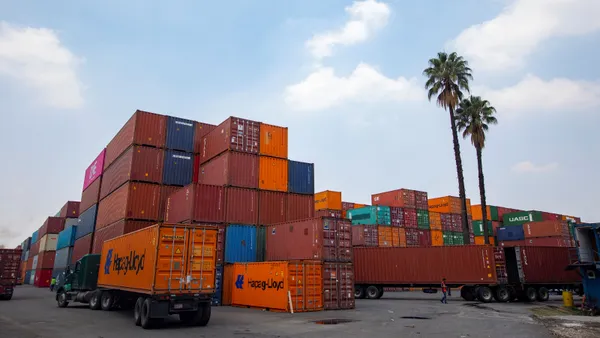 Freight trucks arrive at Pantaco Customs Complex in Mexico City with goods to be shipped to the U.S. The trucks are surrounded by piles of shipping containers.