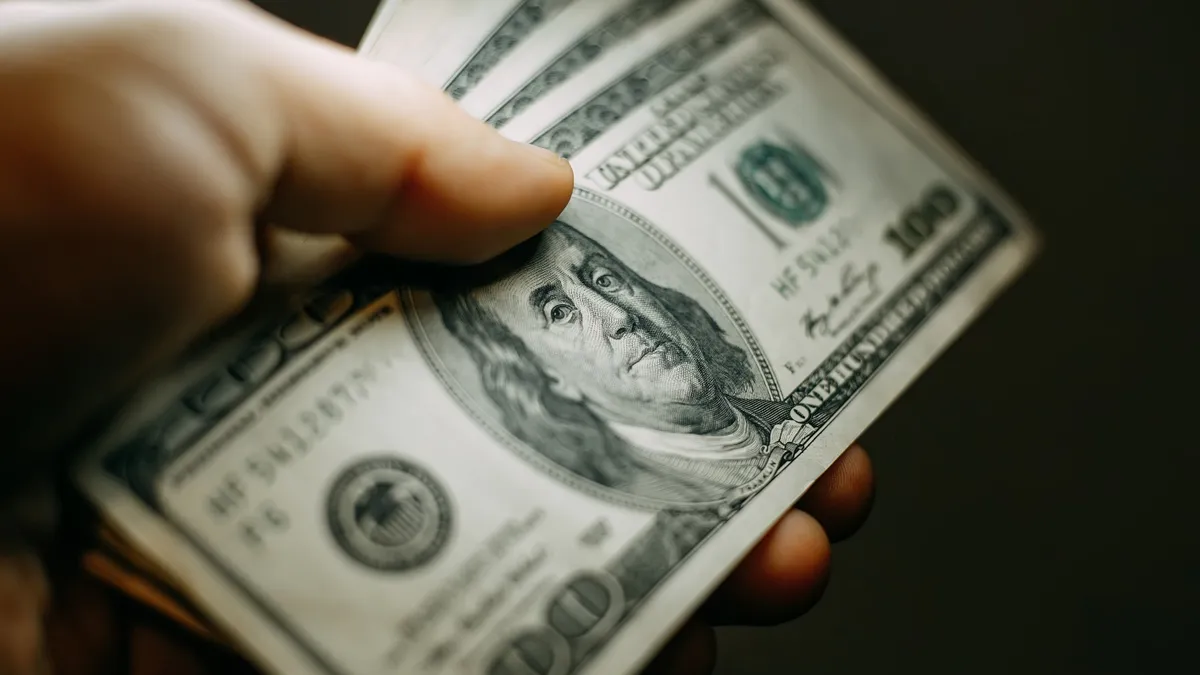 Hand with a stack of hundred US dollars bills, close up