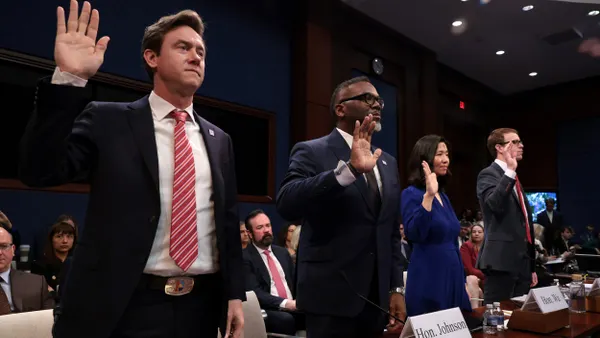 Four people stand with their right hands raised.