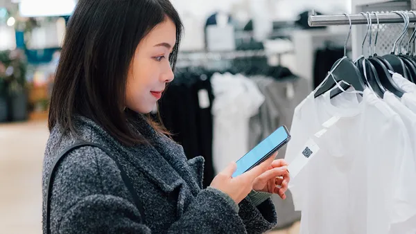 Woman at clothing store taking a picture of a QR code on a t-shirt tag