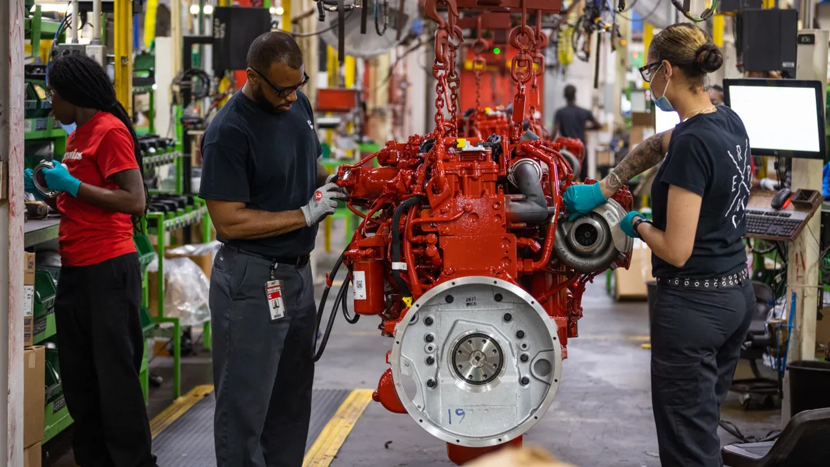 Three employees working in an engine factory.