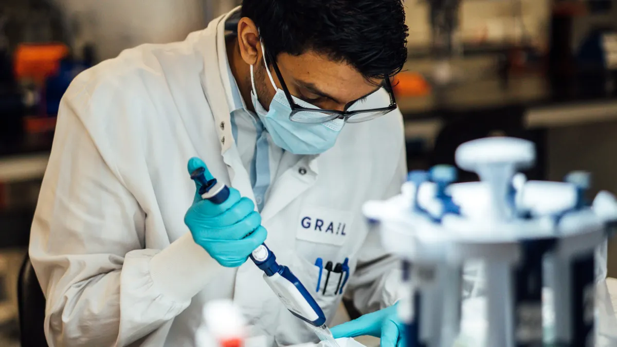 A Grail employee in a white coat works in a lab.