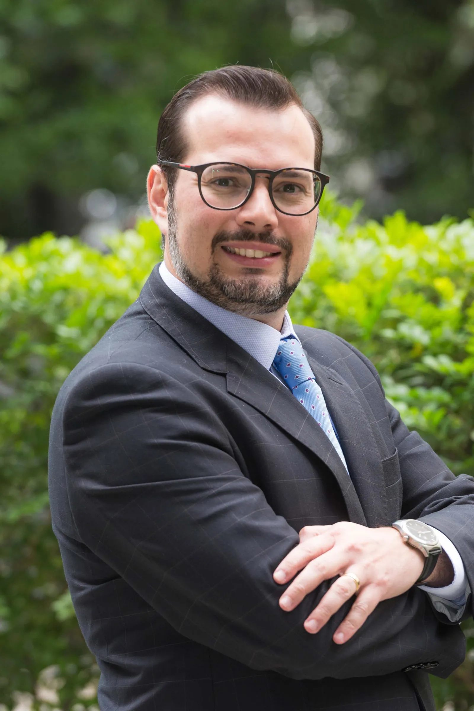 Carlos Silva Filho, a person in a suit and glasses, stands with his arms crossed