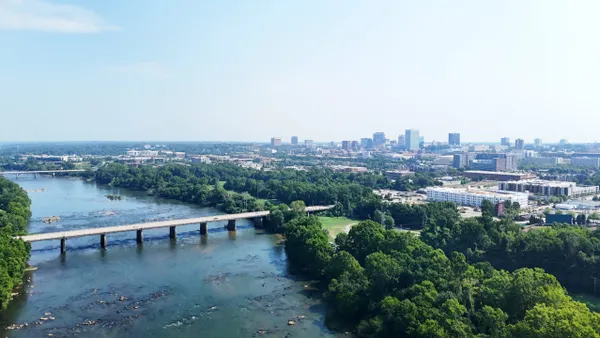 Bridge over broad river with city skyline in background.