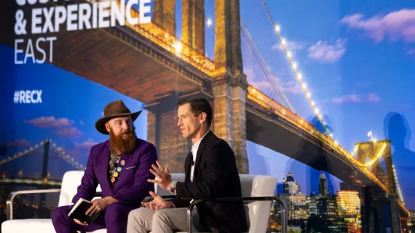 Two people sit on a stage for a fireside chat at a conference.