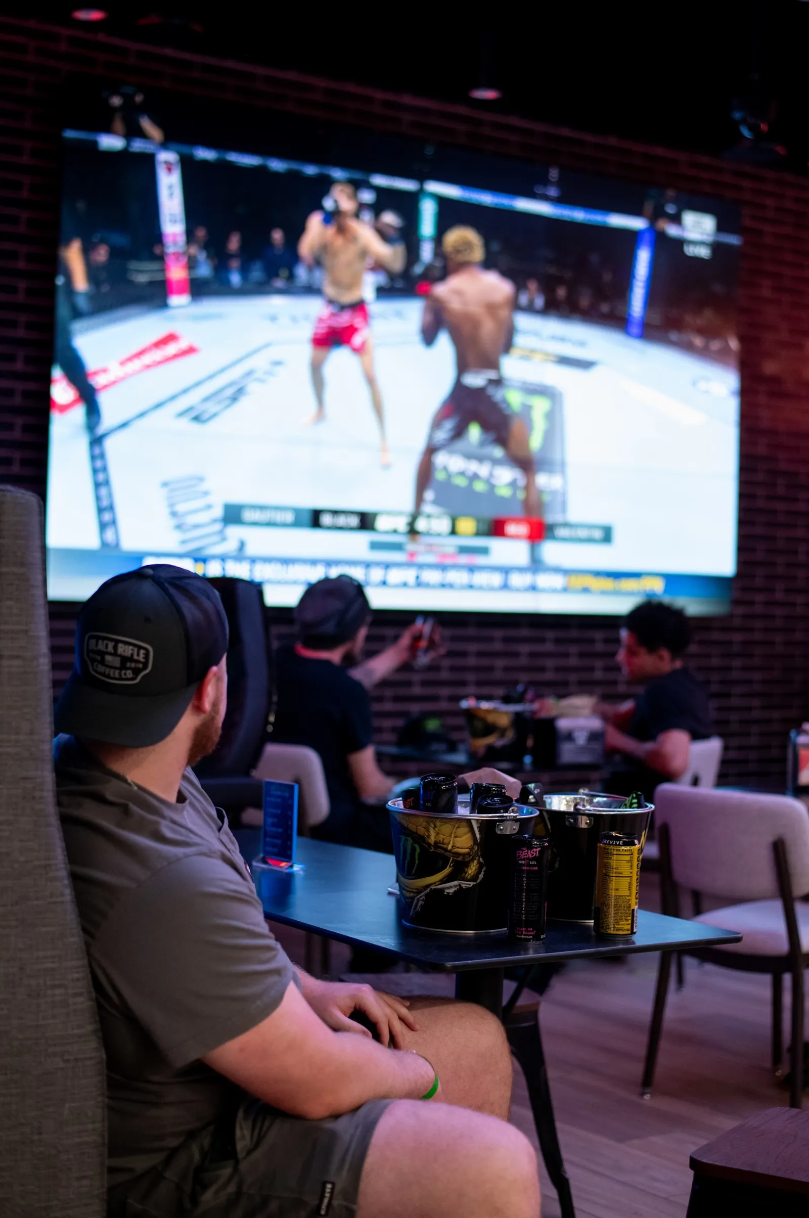 A photo of several people watching a UFC fight on a TV screen.