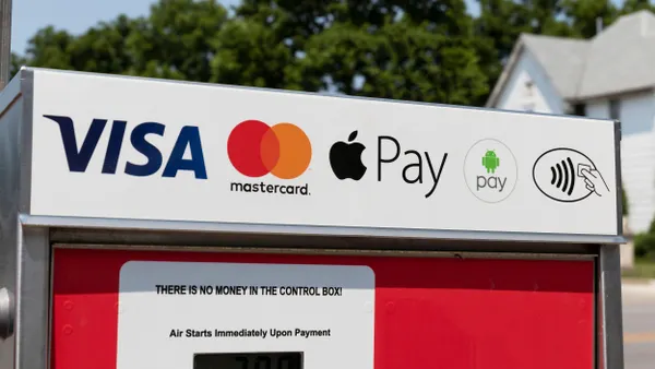 A close-up of a payment kiosk panel showing accepted payment logos—Visa, Mastercard, Apple Pay, Android Pay, and contactless payment—on a white background above a red unit.