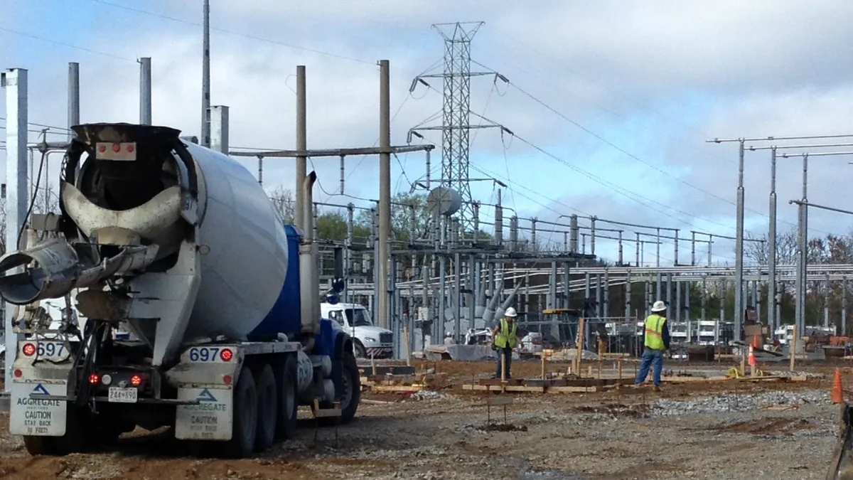 A cement truck sits near an electric substation.