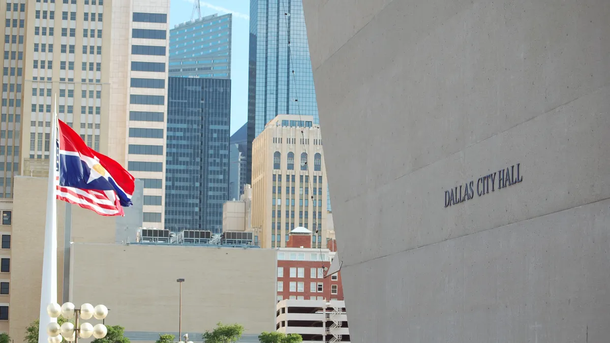 A city hall building looms over the city's downtown, with flags waving on the left.