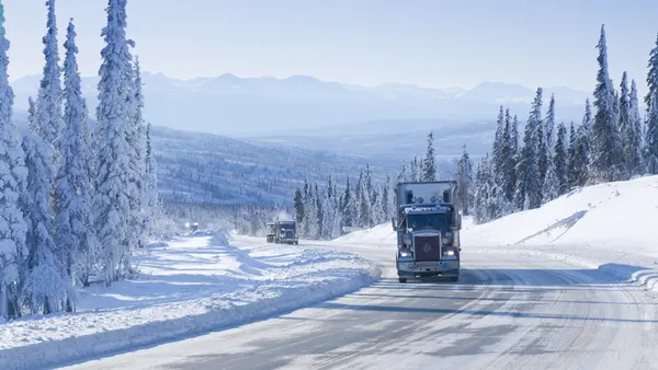 Trucks drive along a snowy highway in Alaska.