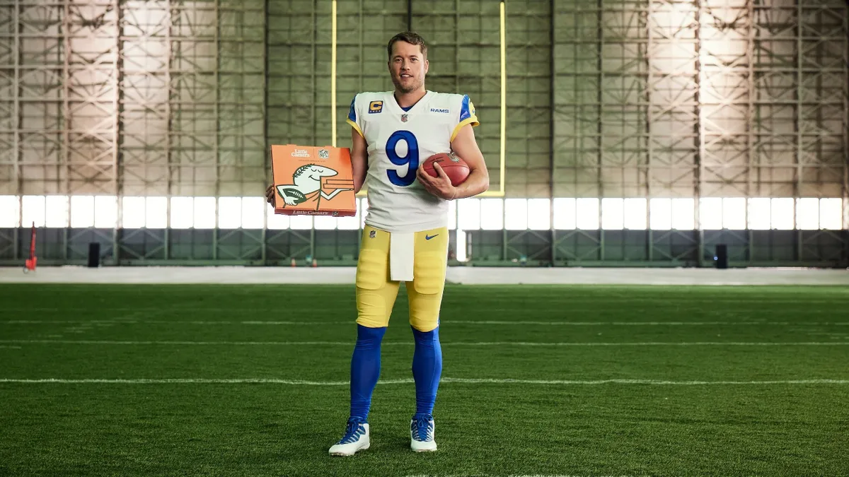 NFL quarterback Matthew Stafford stands and holds a Little Caesars pizza box