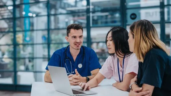 A female doctor uses a laptop while leading a meeting with her medical team