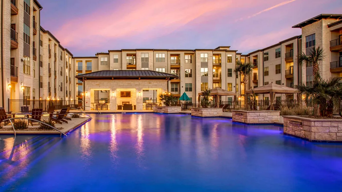 Tan apartment community with a pool in the foreground.