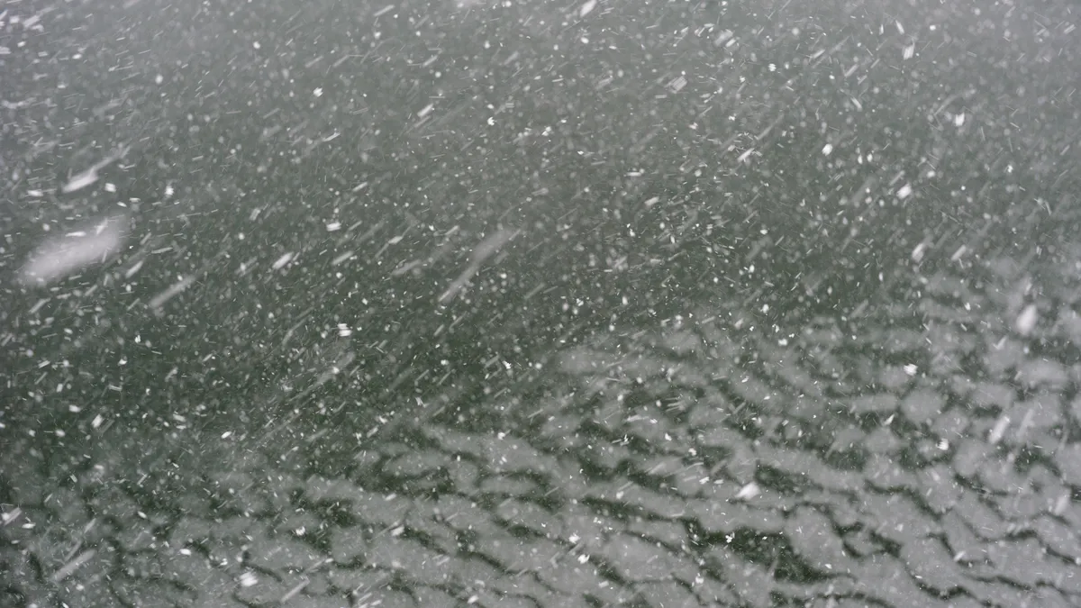 Snow falls over the ocean in Portland, Maine.