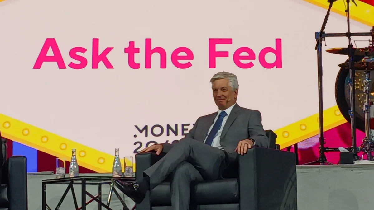 Federal Reserve Governor Christopher Waller sits on a chair on stage.