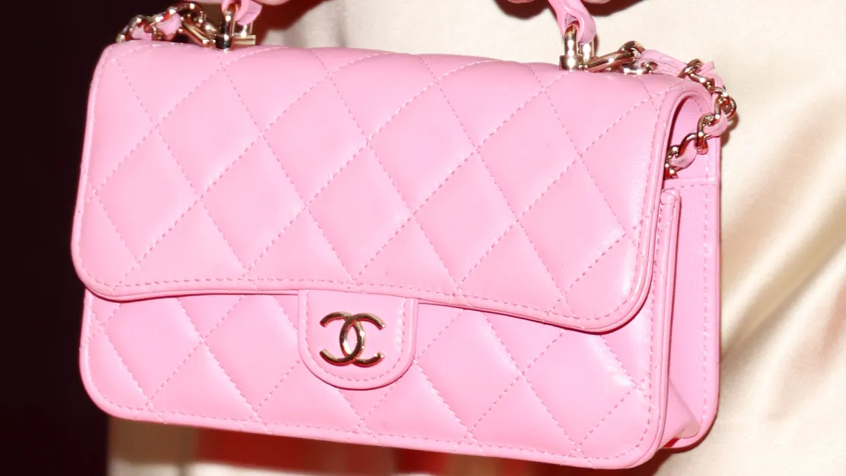 A close up of a person holding a pink Chanel bag with the logo displayed.