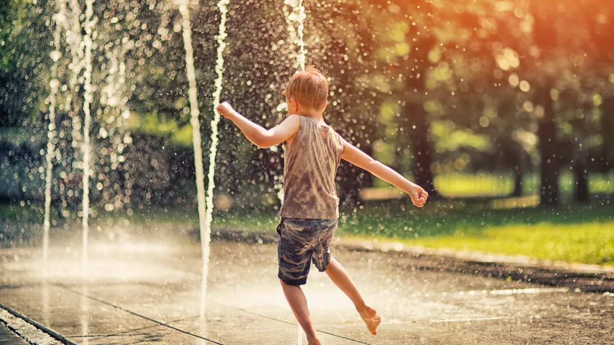 Small child playing in water spraying into the air