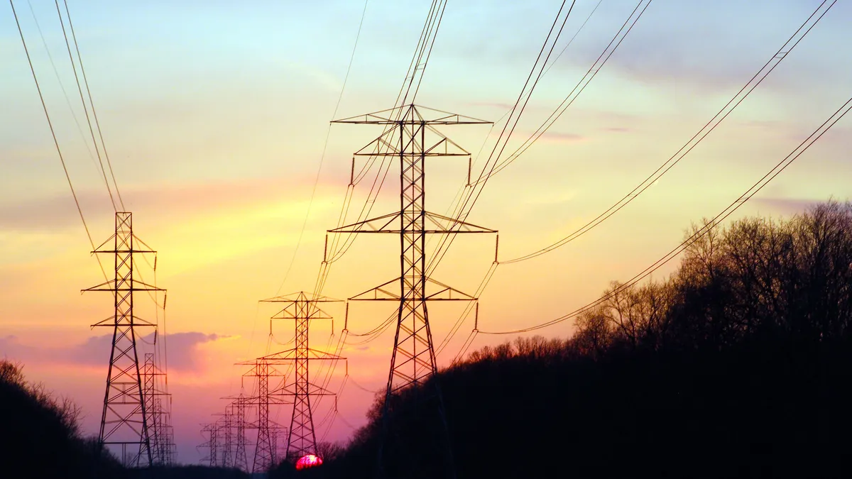 The sun sets behind some transmission lines.