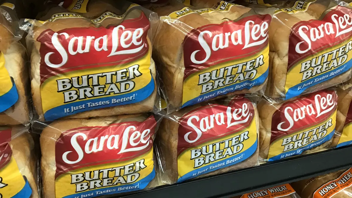 Loafs of Sara Lee bread are stacked on a grocery shelf.