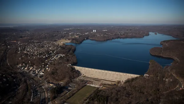 A aerial view of a large reservoir with trees along the shore.