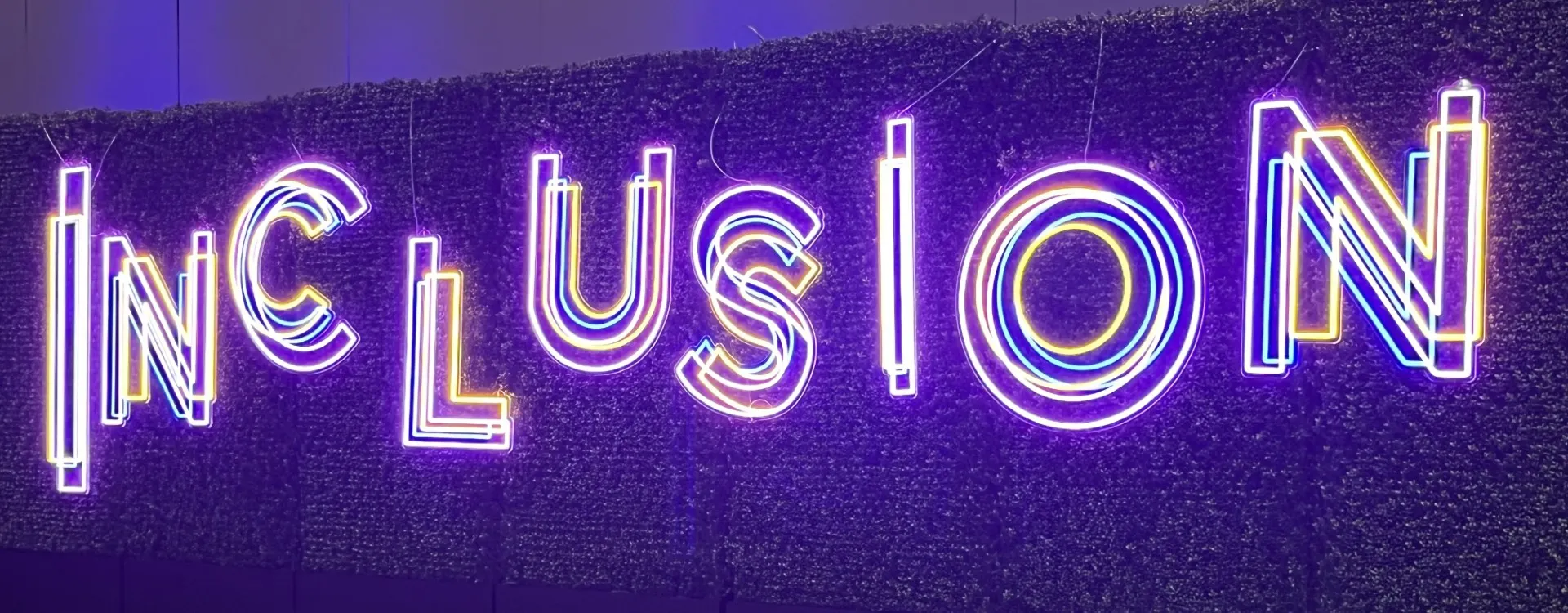 An electric sign displaying the word "inclusion" is seen at a SHRM conference