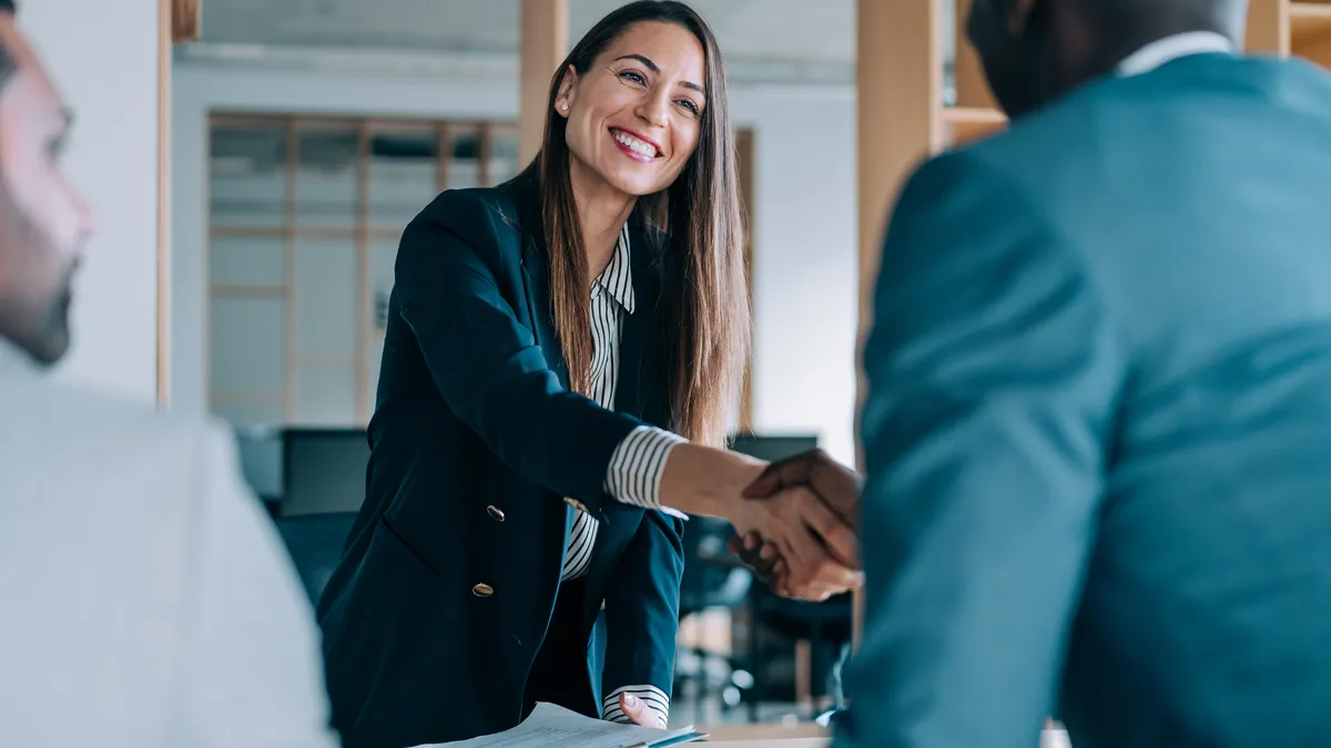 One businessperson shaking another businessperson's hand.