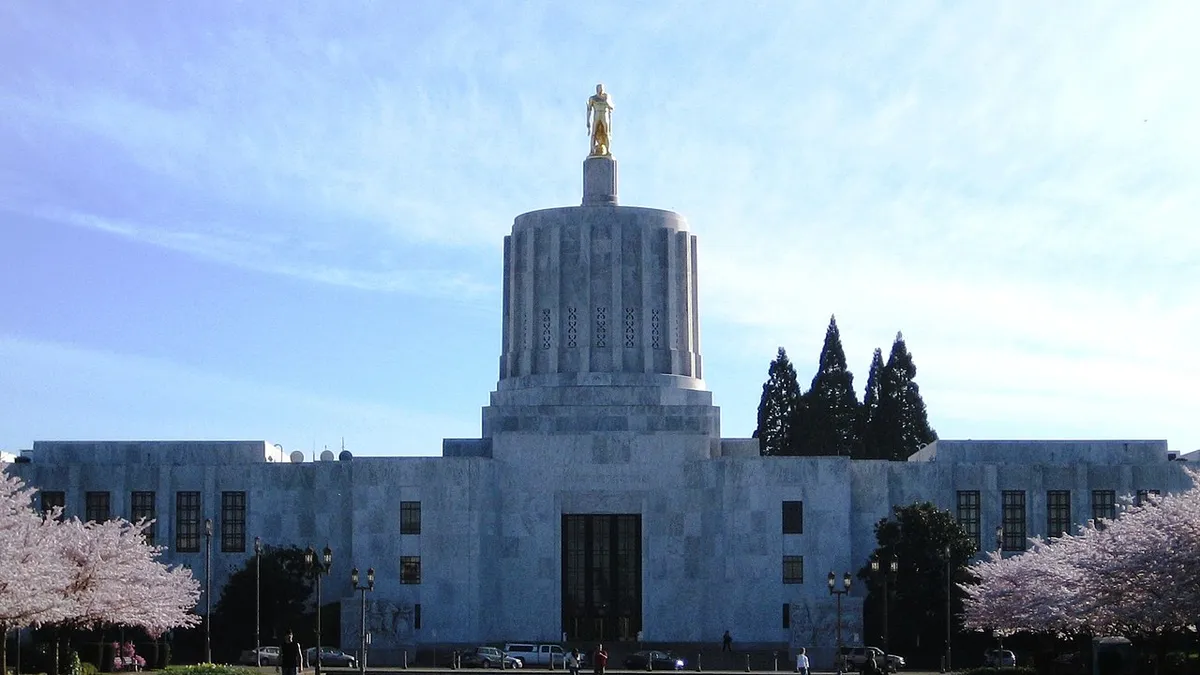 Exterior of a large marble building with a gold statue on top