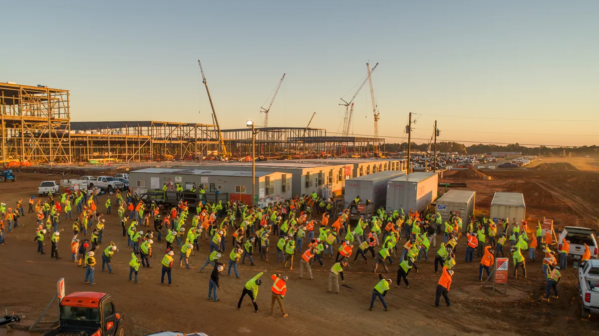 Ab aerial view of several construction workers stretching on a jobsite.