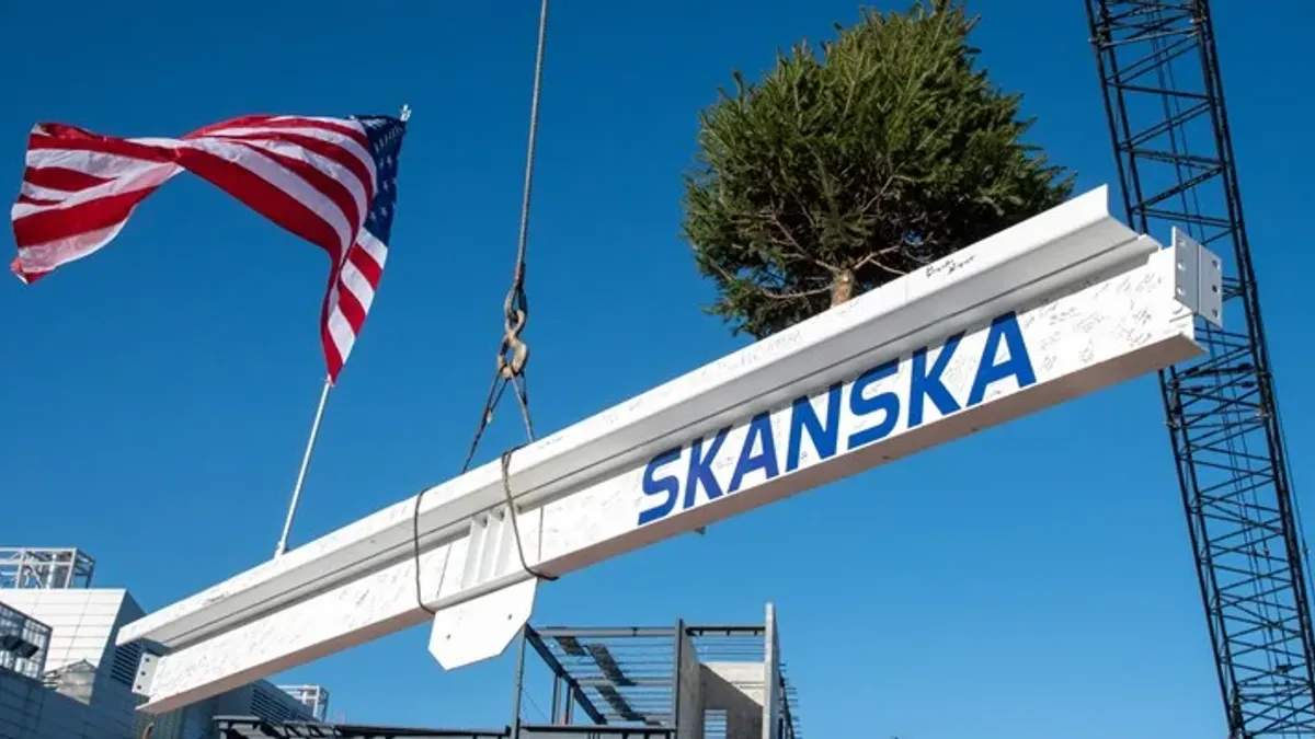 A metal beam hoisted by a crane beneath an American flag.