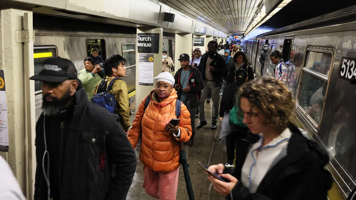 People in a subway station with water on the floor.