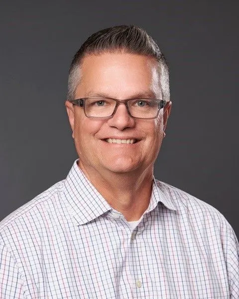 Headshot of a white man in a collared button up shirt