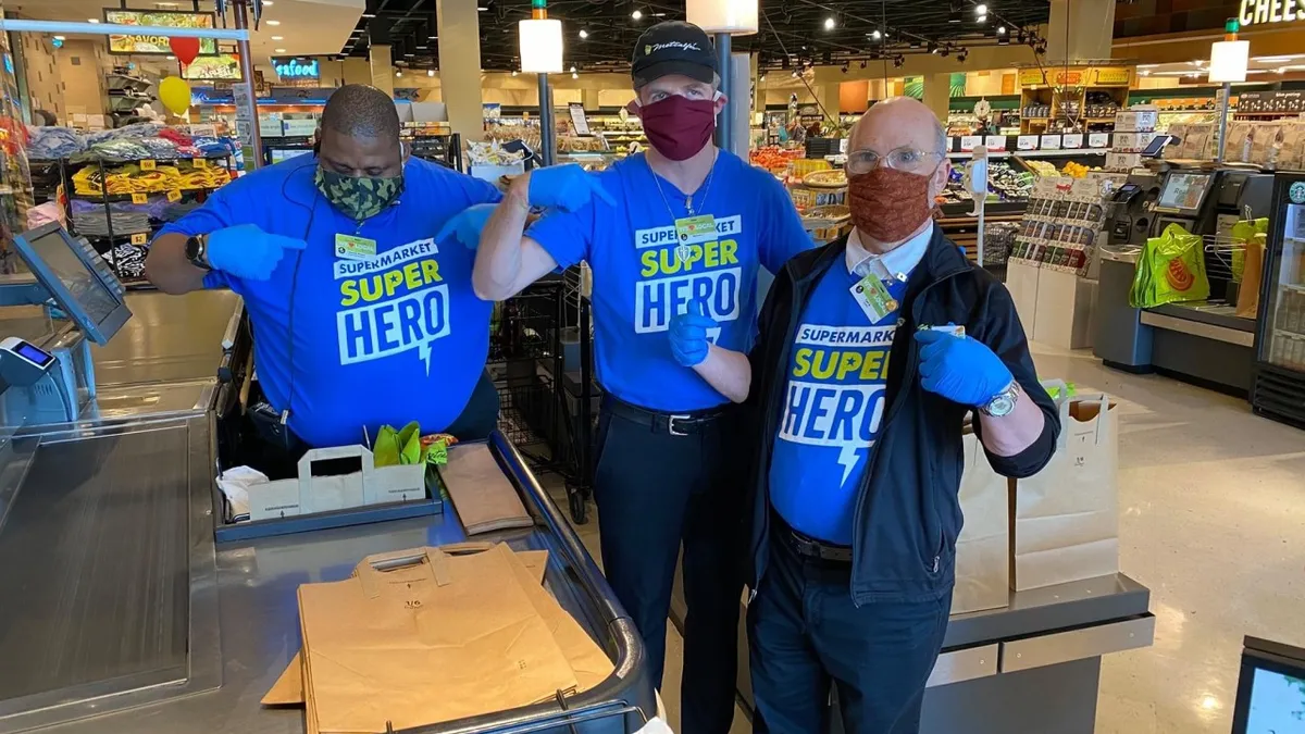 Three people at a grocery store wearing blue t-shirts that say "Supermarket Superhero."