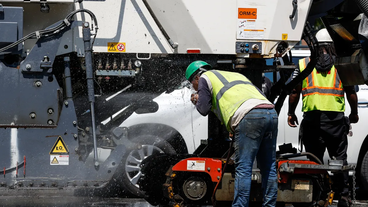 A construction worker sprays water in his face