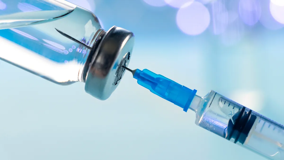 Vaccine vial dose flu shot drug needle syringe on blue background.