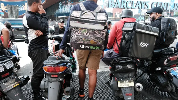 Bicycle gig workers congregate on the street with their packs.