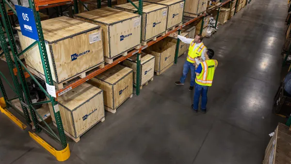 Two people in yellow safety vests stand in a Nefab warehouse with wooden crates