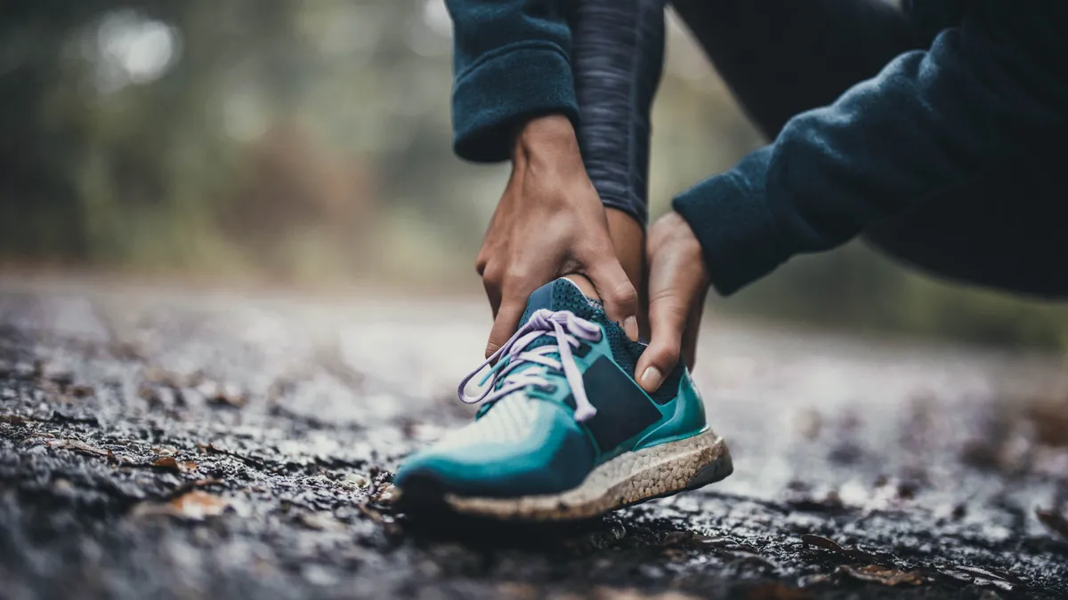 A close-up picture of an athlete holding her ankle in pain at the park.